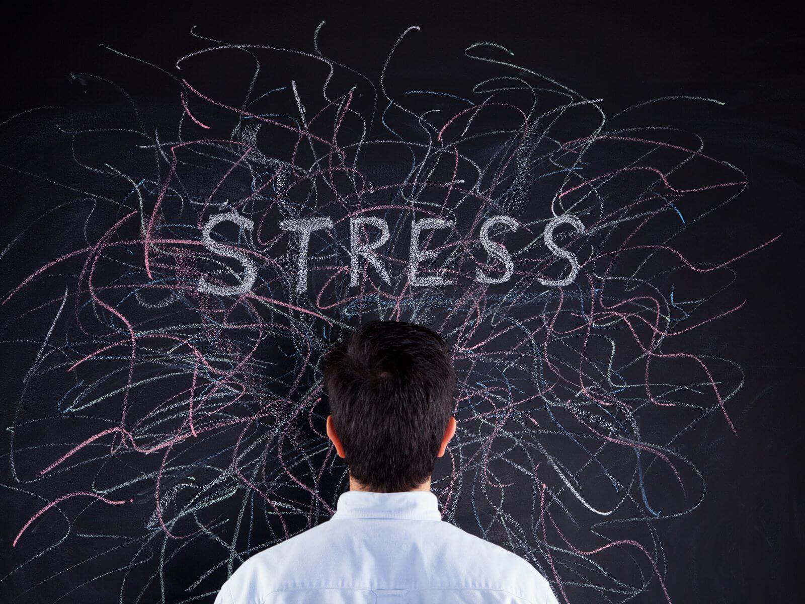 Man looking at blackboard with "stress" written on it