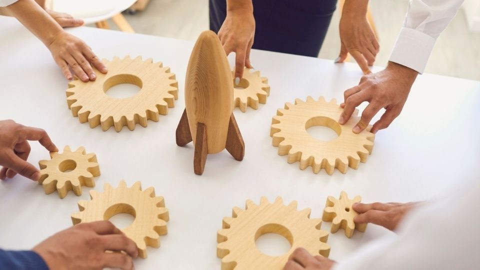 People fitting gears around a rocket representing teamwork